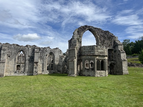 Ruins of Haughmond Abbey showing a large stone arch and Gothic window openings against a blue sky