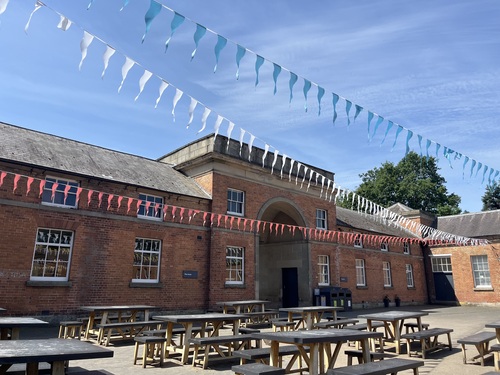 The stable yard courtyard at Attingham Park decorated with colourful bunting on a sunny day