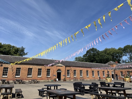 The stable yard courtyard at Attingham Park with yellow and pink bunting against a blue sky