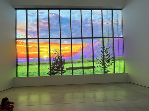 A wide view of the Sunley Window from further back in the gallery, showing the full scale of the work and the green light it casts across the floor