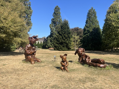 Three bronze Wilde Leute figures by Paloma Varga Weisz standing in the meadow