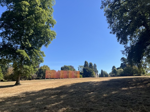Wide view across Wakehurst's meadow with Rana Begum's colourful Mesh installation visible in the distance