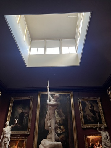 A skylight above the main gallery room, with a marble statue holding a spear below