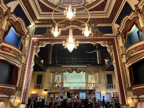 Ornate former opera house interior with gilded balconies and chandeliers, now a pub