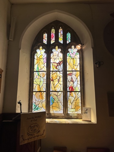 Large three-lancet stained glass window in yellow and red tones