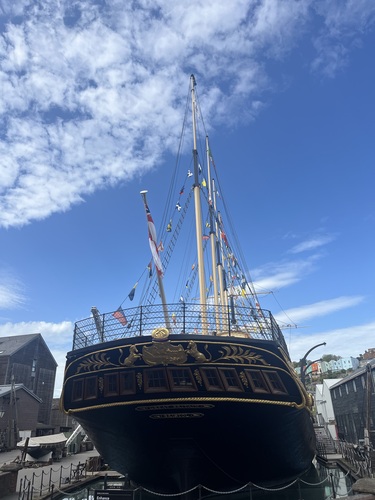 Looking up at the bow of SS Great Britain in dry dock, gold figurehead detail and rigging against a blue sky