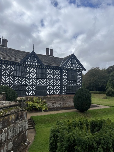 Side view of Speke Hall's black and white timber-framed gables across the lawn