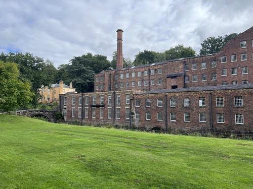 Quarry Bank Mill, with its chimney, seen across the grounds