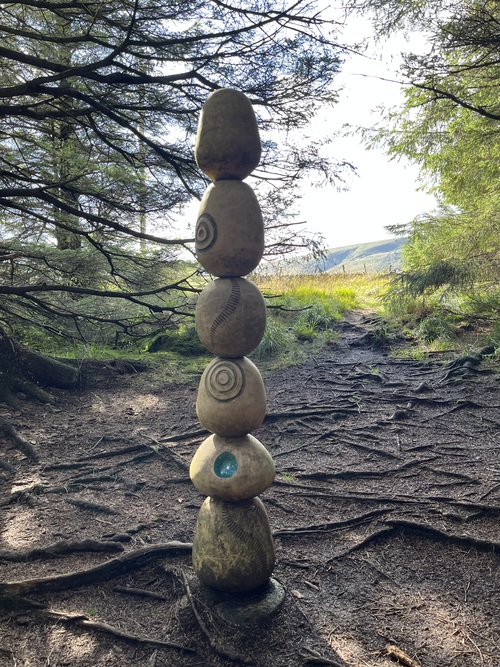 A stacked stone sculpture in pale blue with natural symbols