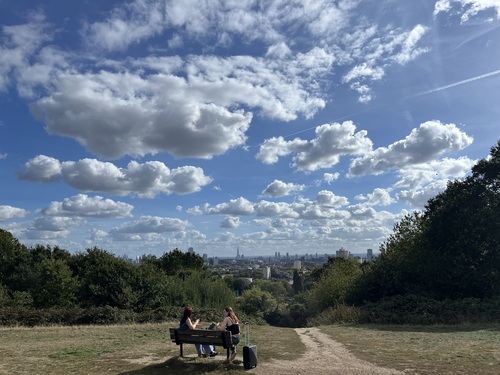 Looking over the London skyline from Parliament Hill, with two people on a bench