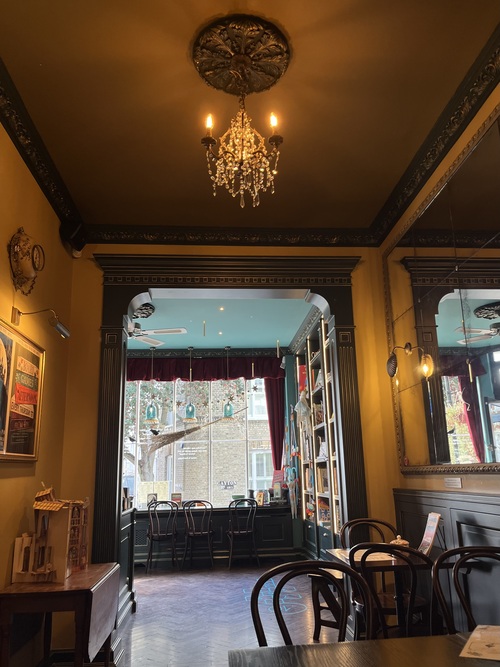 Inside The Well Walk Theatre cafe, with a chandelier, dark panelling and a broomstick hanging in the window