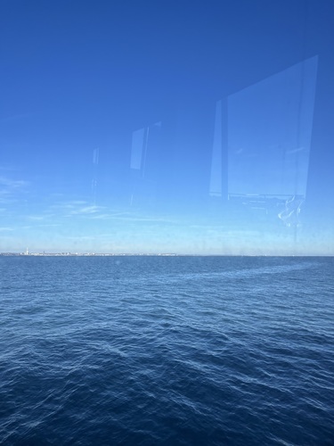 Calm blue sea from the FastCat window, with the Portsmouth skyline and Spinnaker Tower on the horizon
