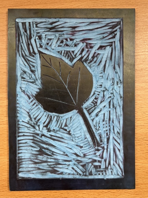 The carved blue lino block, with the leaf standing out from the cut-away background and a solid border around the edge