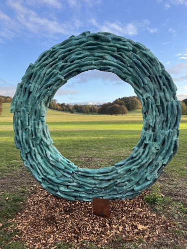 Regeneration by James Wild installed at West Dean Gardens with parkland and autumn trees visible through it